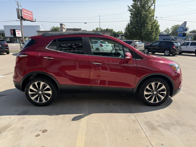 Side view of a red compact SUV parked in a car dealership lot on a sunny day.