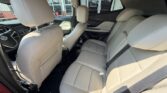 Beige leather rear seats in a sedan with two headrests and a three-seat bench, front seats visible, seat belts fastened, light interior.