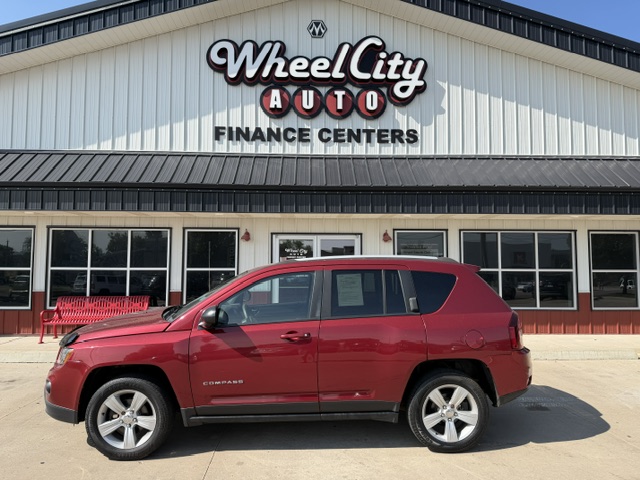 Red SUV parked in front of Wheel City Auto Finance Centers storefront, with the dealership sign visible on a white building.