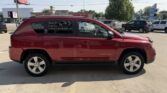 Red mid-size SUV parked in a dealership lot, side view with other vehicles in the background.