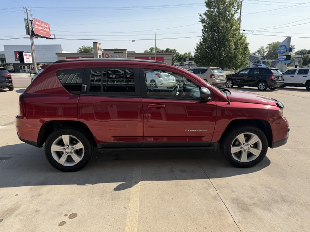 Red mid-size SUV parked in a dealership lot, side view with other vehicles in the background.