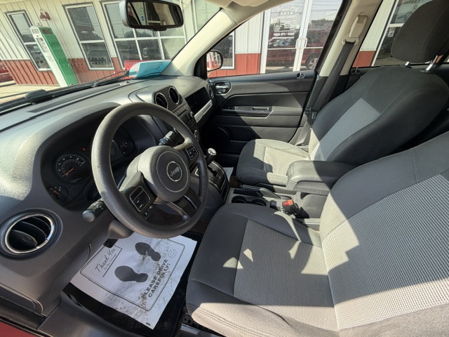 Interior of a Jeep SUV from the driver's side, featuring gray fabric seats, steering wheel, dashboard, center console, and gear shifter
