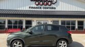 Green SUV parked in front of Wheel City Auto Finance Centers storefront with a red bench nearby.