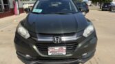 Front view of a dark gray Honda SUV parked at a dealership, with a Wheel City license plate frame and a blue windshield tag.