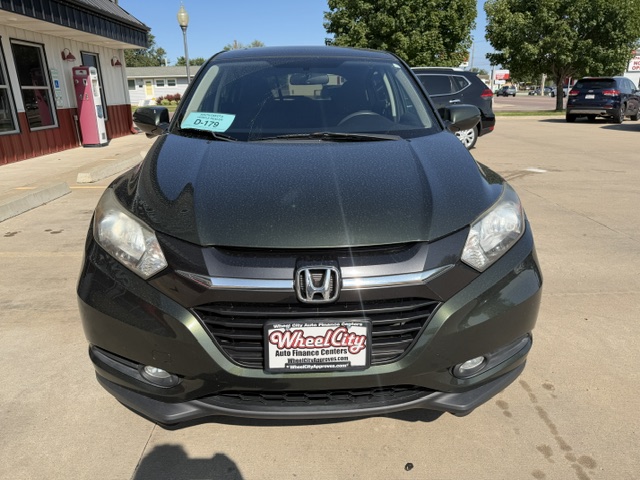 Front view of a dark gray Honda SUV parked at a dealership, with a Wheel City license plate frame and a blue windshield tag.
