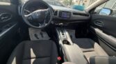 Driver's-side interior of a Honda: steering wheel, center touchscreen, and gear shifter visible among black cloth seats.