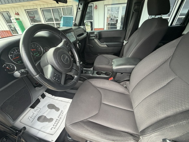 Front interior of a dark Jeep SUV showing the steering wheel, dashboard, center console, and two fabric front seats inside.