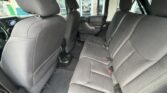 Interior of a dark cloth-seat SUV viewed from the rear passenger area, showing the back bench seat and front seats with legroom visible.