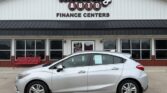 Silver sedan parked in front of Wheel City Auto Finance Centers storefront, with a red bench and large windows behind the car.