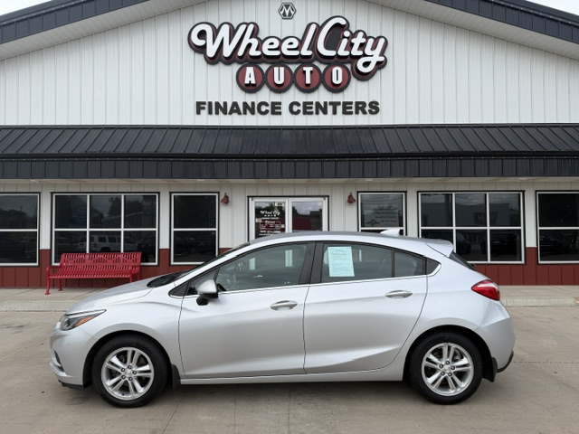 Silver sedan parked in front of Wheel City Auto Finance Centers storefront, with a red bench and large windows behind the car.
