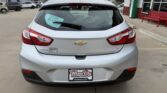 Rear view of a silver Chevrolet hatchback at a dealership, with a Wheel City license plate frame and a D-172 tag on the rear window.