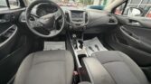 Interior of a Chevrolet car from the driver's seat, showing steering wheel, dashboard, center console, and front passenger seat.