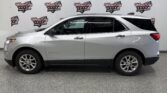 Side view of a silver Chevrolet Traverse SUV parked indoors with a Wheel City Auto Finance Centers banner in the background.