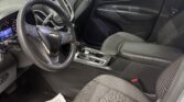 Driver's seat interior of a Chevrolet SUV, steering wheel with logo, dashboard, center console, and a paper floor mat on the driver side