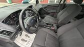Front interior of a Ford sedan showing the steering wheel, dashboard, and two front seats with center console visible in the foreground.
