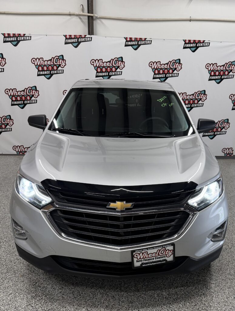 Front view of a silver Chevrolet SUV in a dealership, with Wheel City Auto Finance Centers backdrop.