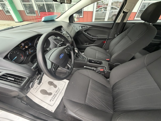 Front interior of a Ford sedan showing the steering wheel, dashboard, and two front seats with center console visible in the foreground.