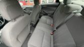 Dark cloth interior of a sedan, rear bench seat with three seat belts and front seats visible through the cabin doors.