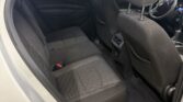 Interior of a gray car with the rear and front seats visible through an open rear door; black fabric seats with headrests, and a Chevrolet steering wheel in the front.