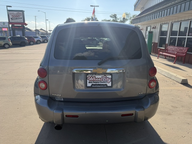 Rear view of a gray Chevrolet Uplander minivan in a dealership lot, with a Wheel City Auto Finance Centers license plate frame.