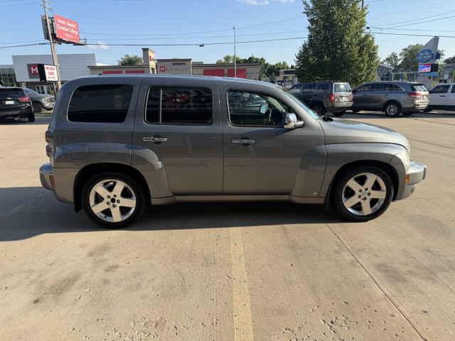 Side view of a silver boxy SUV parked in a dealership lot with other vehicles nearby.