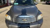 Front view of a dark gray Chevrolet SUV parked in a lot, chrome grille with bowtie emblem, windshield with a green purchase tag, Wheel City license plate frame.