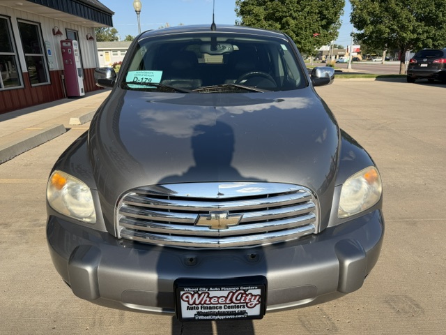 Front view of a dark gray Chevrolet SUV parked in a lot, chrome grille with bowtie emblem, windshield with a green purchase tag, Wheel City license plate frame.