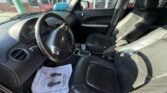 Interior of a car with black leather front seats, steering wheel, and center console visible from the driver’s side door.