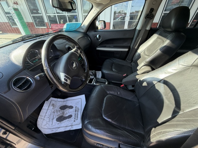 Interior of a car with black leather front seats, steering wheel, and center console visible from the driver’s side door.