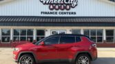 Red SUV parked in front of Wheel City Auto Finance Centers storefront with glass doors and windows in the background.
