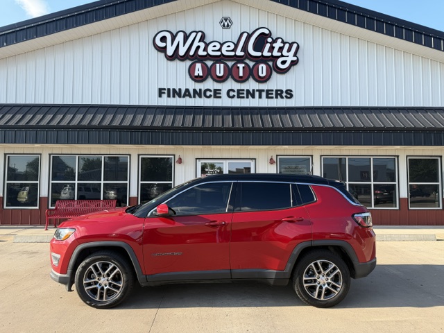 Red SUV parked in front of Wheel City Auto Finance Centers storefront with glass doors and windows in the background.