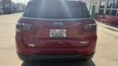 Rear view of a red Jeep SUV in a dealership lot with a Wheel City license plate frame on the bumper.