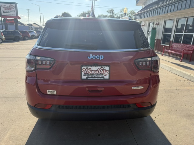 Rear view of a red Jeep SUV in a dealership lot with a Wheel City license plate frame on the bumper.