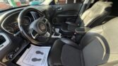 Inside a Jeep SUV with black leather seats, steering wheel with Jeep badge, center console, and a dealership paper on the floor mat.