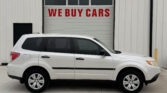 White SUV parked in front of a garage door with a bold red 'WE BUY CARS' sign on it