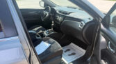 Interior of a parked car viewed from the open door: steering wheel, center console, and dashboard visible with papers on the front passenger seat.