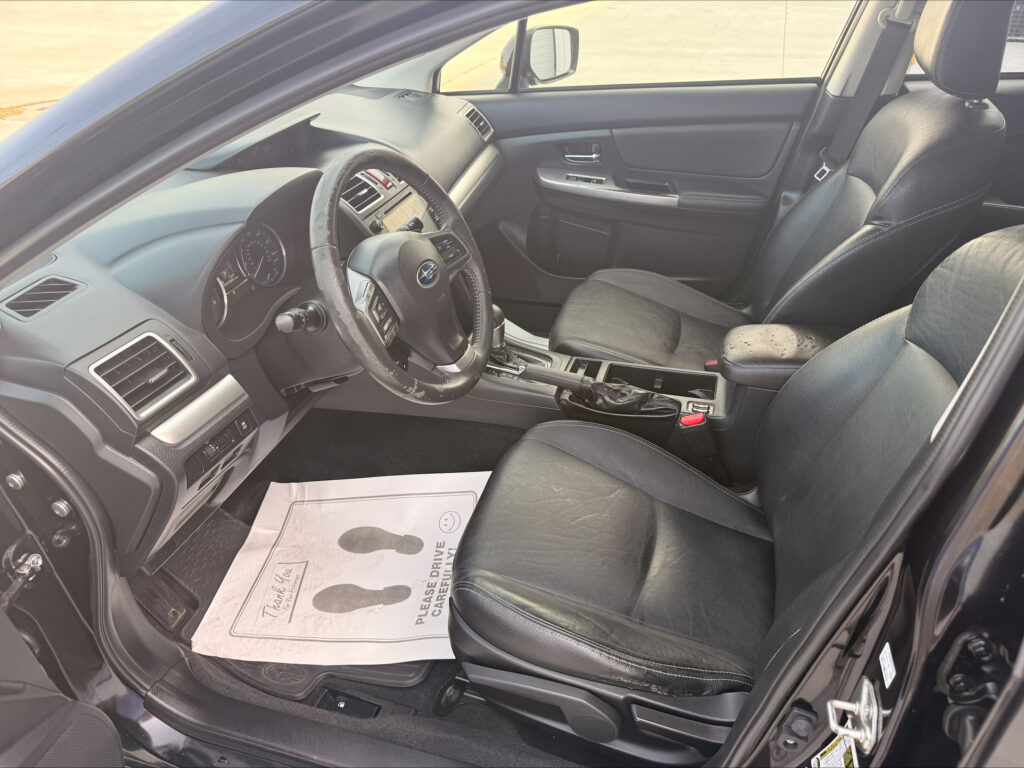 Interior view of a black SUV from the driver's side, showing the steering wheel, dashboard, center console, and leather seats with a paper floor mat on the driver's side