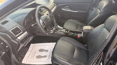 Interior view of a black SUV from the driver's side, showing the steering wheel, dashboard, center console, and leather seats with a paper floor mat on the driver's side