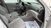 Interior of a light gray car: front seats, steering wheel, center console, and dashboard visible from the open driver-side door.",