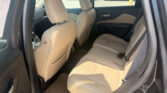 Beige leather back seats of a car with the rear door open, parking lot visible outside the window.