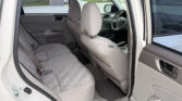 Rear-passenger area of a light-colored SUV with gray fabric seats; front seats and steering wheel visible through the open door.