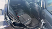 Open rear passenger door view of a black leather car interior with back seats and front seat backs visible.
