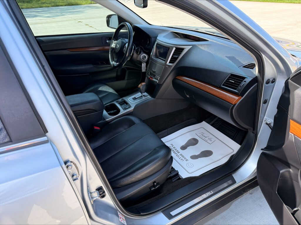 Open driver’s-side view of a silver SUV interior, showing the steering wheel, dashboard, and center console with wood trim.