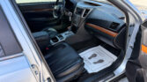 Open driver’s-side view of a silver SUV interior, showing the steering wheel, dashboard, and center console with wood trim.