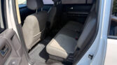 Rear interior of a light-colored SUV with gray leather seats and rubber floor mats, viewed from the open rear door