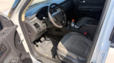 Interior view from the driver’s side showing the steering wheel, dashboard, center console, and a bottle on the floor mat near the pedals (Ford).