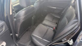 Interior of a dark car showing the rear bench seat and front seats with headrests, view from open rear door