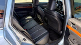 Backseat area of a car with black leather seats, front seats visible, door panel with wood trim, and a window sticker hanging in the rear window.