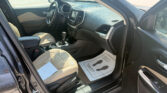 Open front driver’s door of a black SUV, view of beige leather seats and center console.