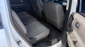 View of the car's back seat area with gray leather seats, seen from the open rear door; front seats and dashboard visible.